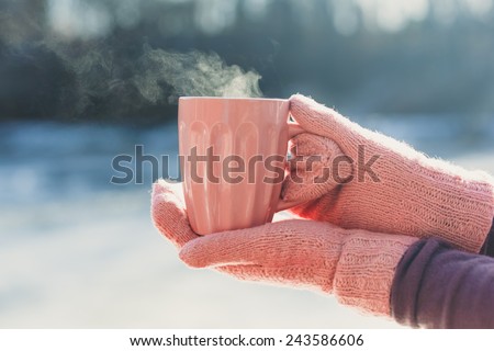 Female hands  in mittens holding cup with hot  tea or coffee. Winter and Christmas time concept