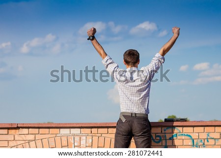 Cheerful business man standing outdoor and rising hands