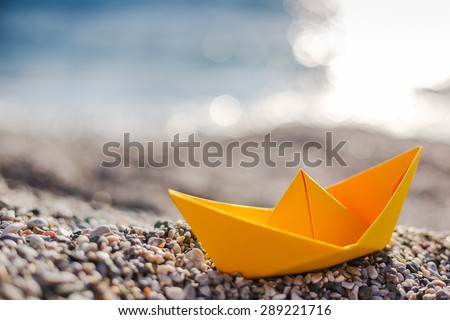 Yellow paper boat on beach on sunset time