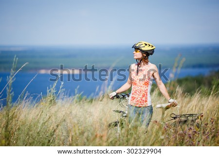 Mountain biking - woman with bike enjoy summer vacation in the beautiful meadow