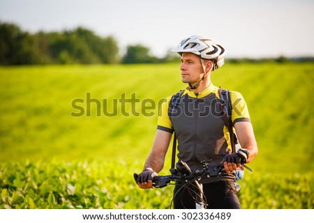 Handsome young man biking in the countryside