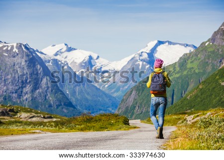 Hitchhiking tourism concept.Travel hitchhiker woman walking on road during holiday travel
