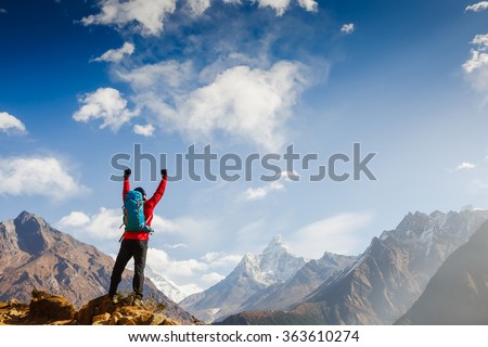 Winner / Success concept. Hiker cheering elated and blissful with arms raised in the sky after hiking to mountain top summit above the clouds