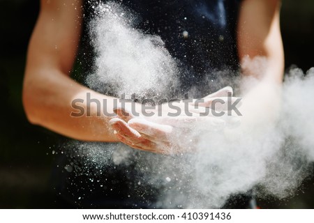 Climber woman coating her hands in powder chalk magnesium and preparing to climb outdoor, close up