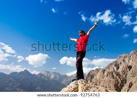 hiker at the top of a rock with his hands up