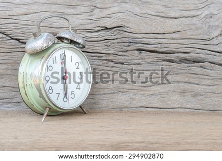 old green clock alarm on wood background