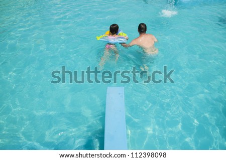 father and daughter bathe in the pool in summertime