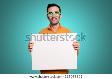 man with orange sweater holding blank white board on blue background