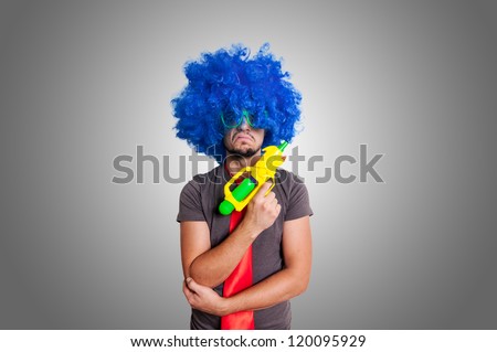 Funny guy with blue wig and water gun on grey background