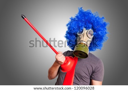 funny guy with gas mak, blue wig and red plunger on grey background