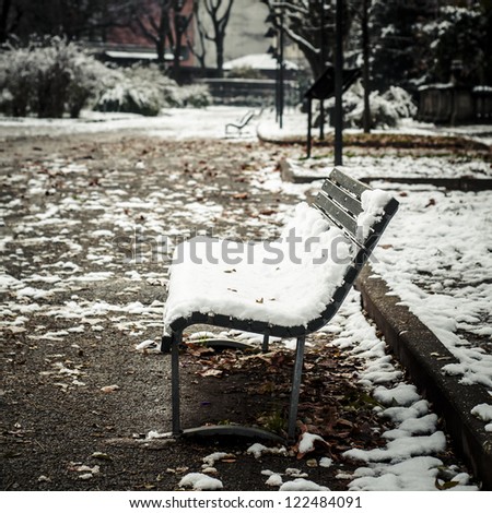 bench covered with snow in winter landscape with trees