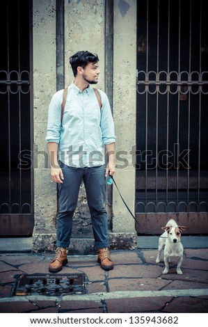 stylish man in the street with a jack russel in front of a wall