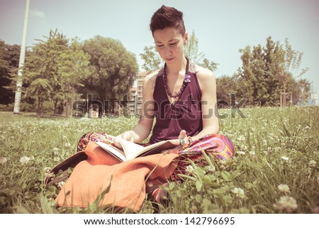 beautiful hipster short hair woman reading book in the park in the city