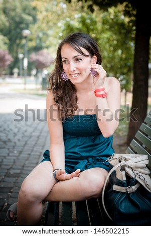 beautiful woman sitting in the bench in city
