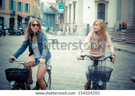 two beautiful blonde women shopping on bike in the city