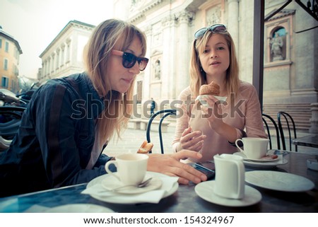 two beautiful blonde women talking at the bar in the city