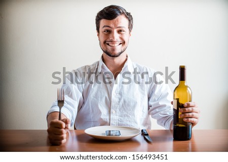 young stylish man with white shirt and phone on the dish behind a table