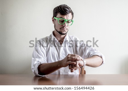 young stylish man with white shirt time wristwatch behind a table