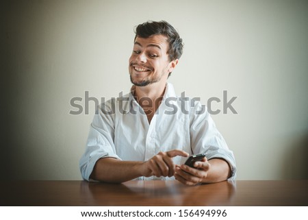 young stylish man with white shirt on the phone behind a table