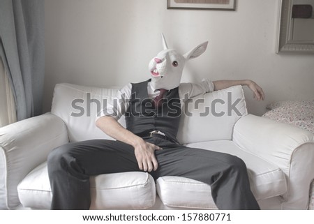 rabbit mask man sitting on sofa at home