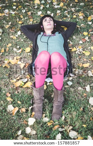 young beautiful woman listening to music at the park in autumn
