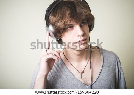 stylish young blonde hipster man listening to music on white background