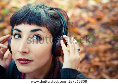 beautiful young woman listening to music in the city autumn