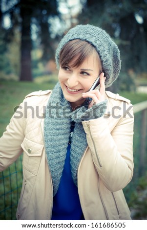 beautiful young woman on the phone at the park in autumn