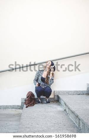 beautiful young blonde hipster woman listening music in urban landscape