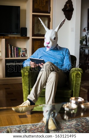 elegant business multitasking rabbit mask man using devices at home