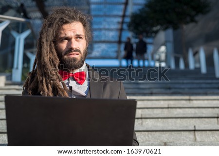 Stylish elegant dreadlocks businessman using notebook in business landscape