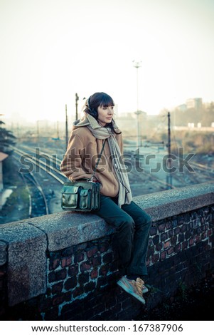 beautiful young woman listening to music headphones  in the city winter