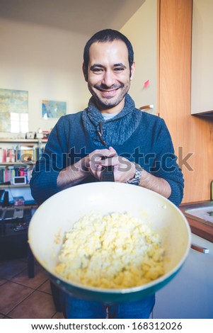 Man showing a pan with scrambled eggs in the kitchen