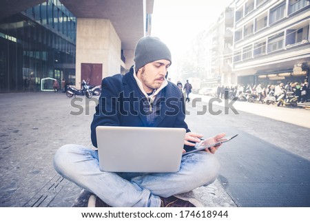 multitasking man using tablet, laptop and cellphone connecting wifi in the city street urban