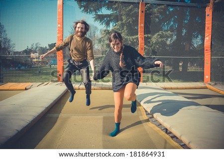 young modern stylish couple urban city jumping trampoline outdoors