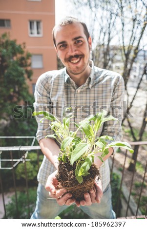handsome stylish man holding basil plant at home