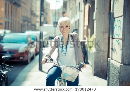 beautiful young blonde short hair hipster woman with bike in the city