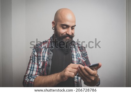 hipster long bearded and mustache man with shirt squares calling with cellphone