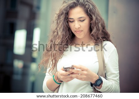 beautiful curly long brunette hair moroccan woman using smart phone in the city