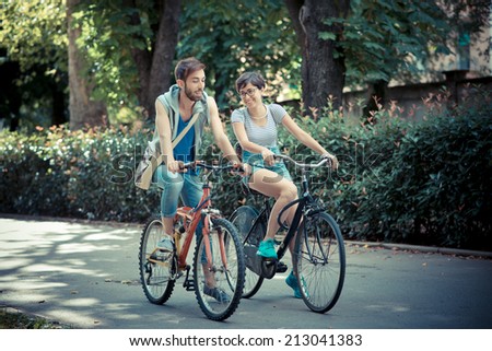 couple of friends young  man and woman riding bike in the city