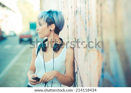 young beautiful short blue hair hipster woman with headphones music in the city