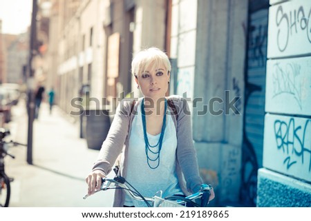beautiful young blonde short hair hipster woman with bike in the city