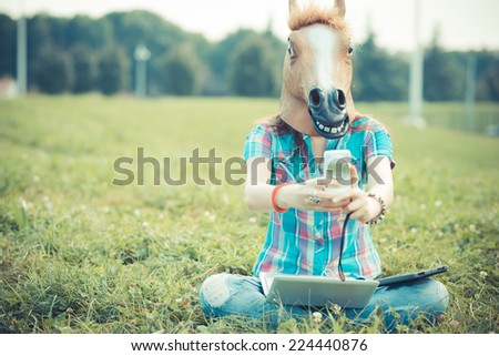 horse mask unreal hipster woman using technology in the park