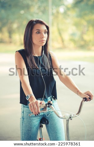 young beautiful brunette straight hair woman using bike and smartphone listening music outdoor