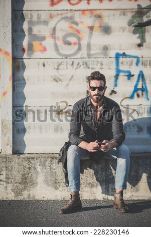 young handsome attractive bearded model man using smartphone in urban context