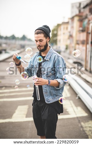 young handsome bearded hipster man blowing bubbles soap in the city