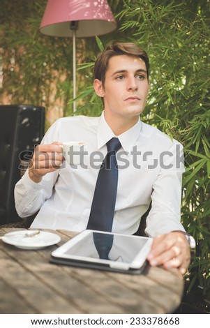 young handsome elegant blonde model businessman working with tablet and smart phone at the bar