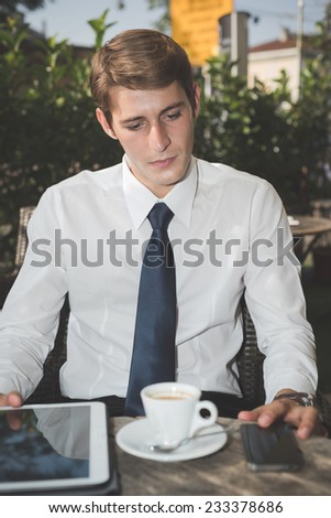 young handsome elegant blonde model businessman working with tablet and smart phone at the bar
