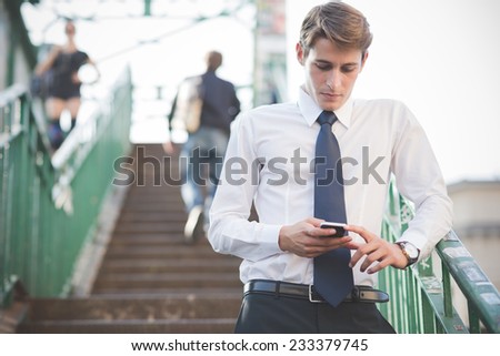 young handsome elegant blonde model man using smartphone in the city