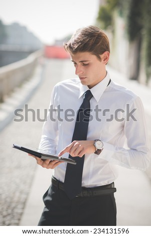 young handsome elegant blonde model man using tablet technological device in the city